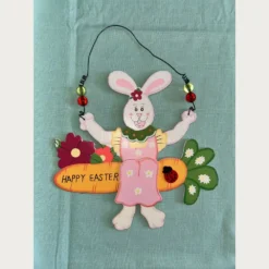 Ξύλινο κρεμαστό λαγουδάκι που κάθεται πάνω σε ένα μεγάλο καρότο . Happy Easter