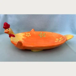 Κεραμική πιατέλα σε σχήμα μιας χαρούμενης κότας σε έντονο πορτοκαλί χρώμα, στολισμένη με κίτρινα και πράσινα λουλούδια